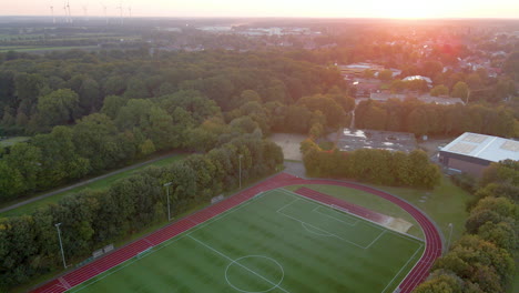 campo de fútbol y exuberante bosque verde durante la puesta de sol en sogel, baja sajonia, alemania