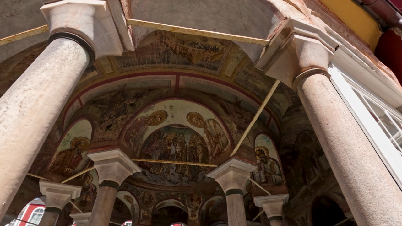 View the intricate design and colors of the old frescoes in a historic building. Notice the tall columns and how they support the ceiling.