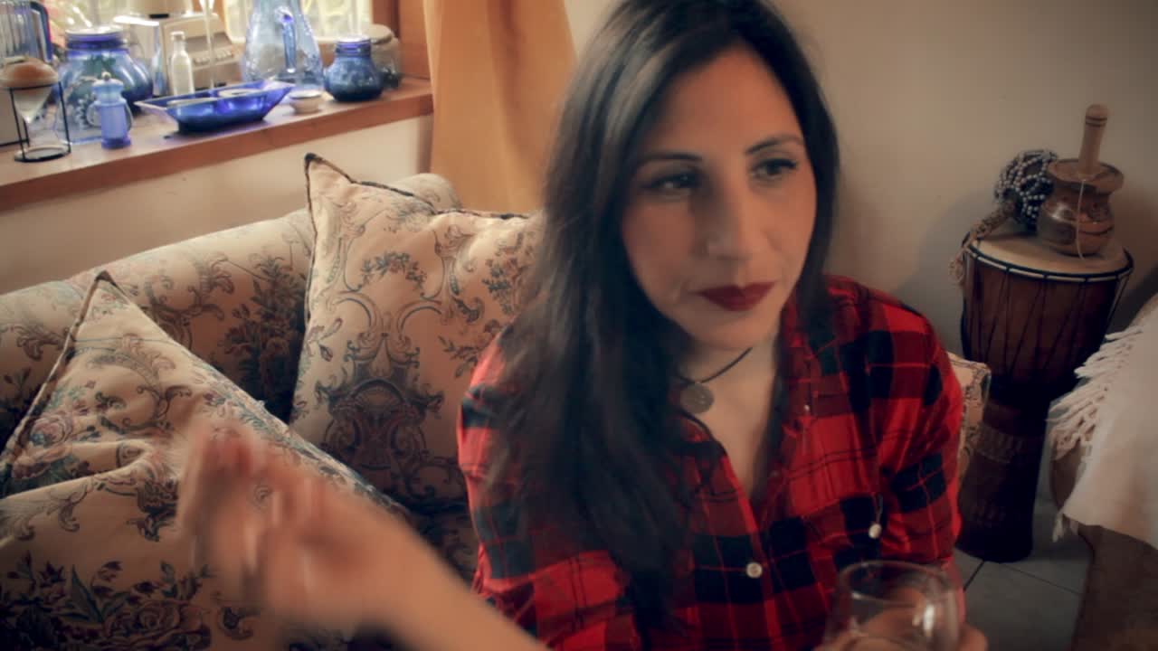 toma frontal de una actriz sentada en el sofá fumando un cigarrillo y bebiendo cerveza, pensando en su próximo paso