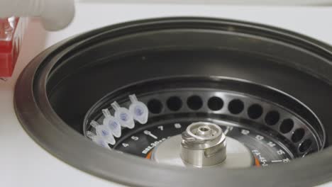 Unrecognizable-lab-technician-loading-test-tubes-into-medical-laboratory-centrifuges