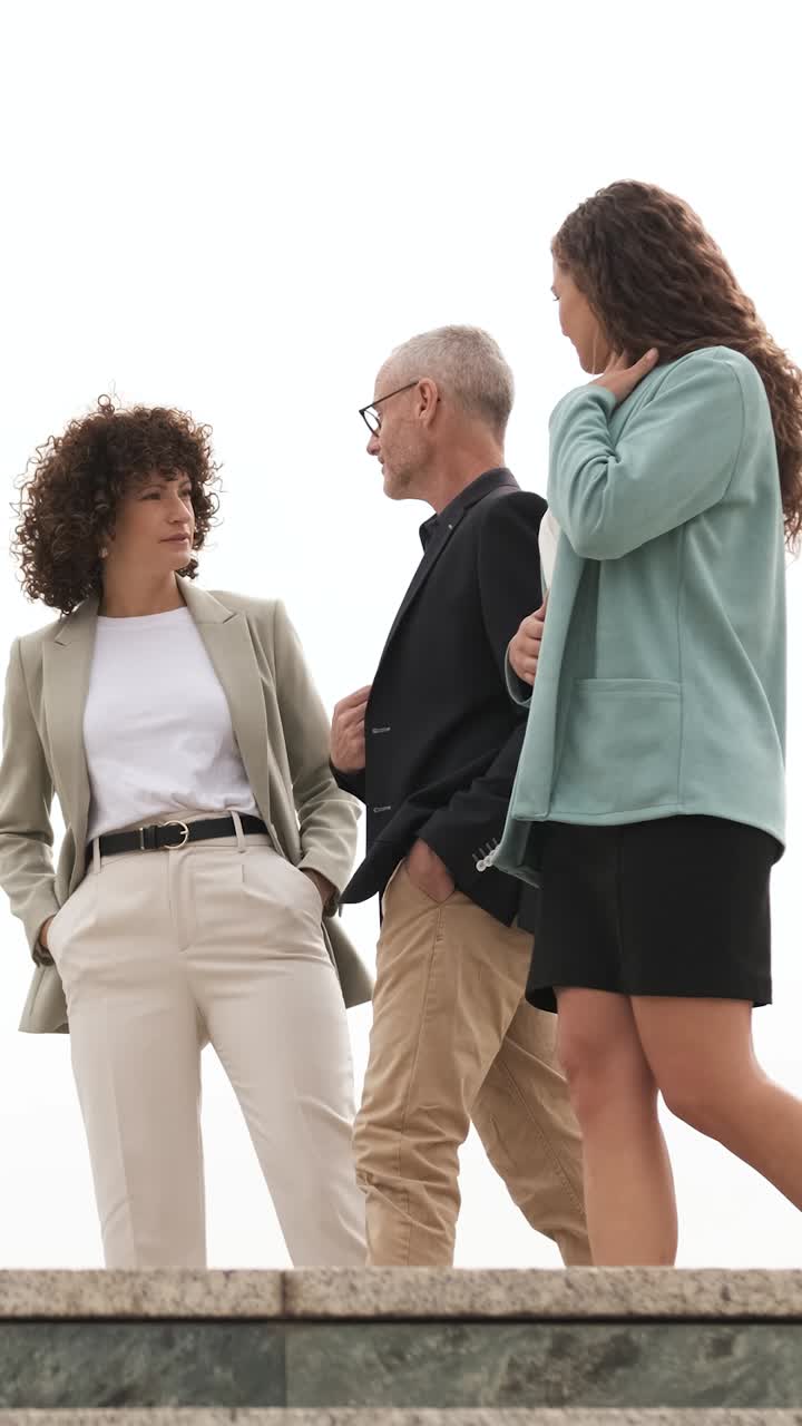 Engaging business professionals walking and conversing in an urban environment. Vertical