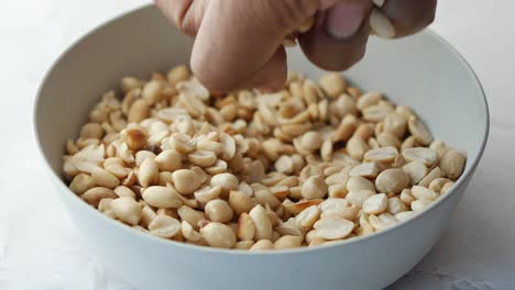 Close-up-of-hand-pick-peanut-from-a-bowl-on-table-,