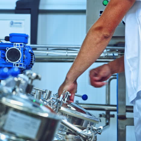 modern factory of dairy products indoors. worker opens metal mixer inside the milk plant. cheese production process. contemporary equipment for making fresh cheese. close-up.