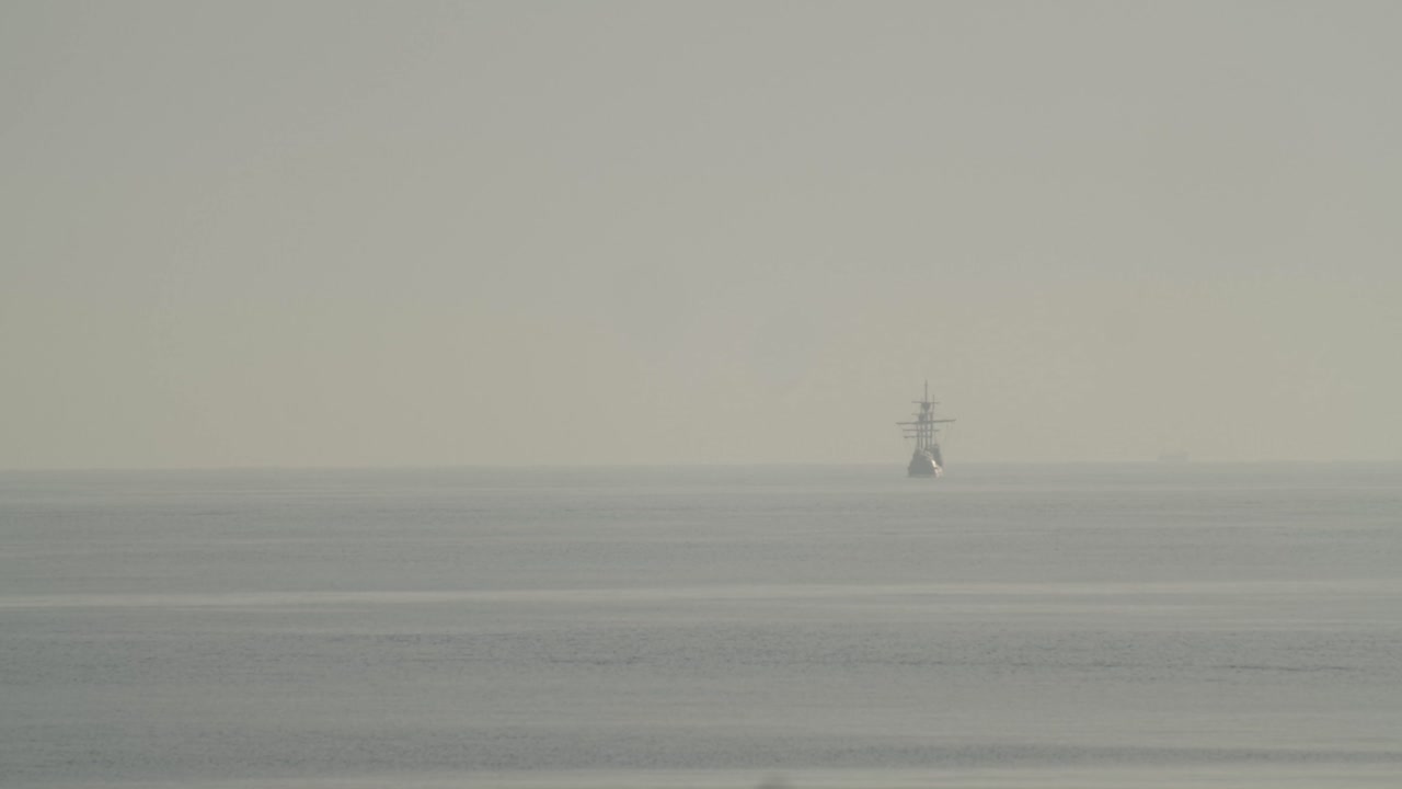 페르디난드 마젤란 나오 빅토리아 카락 보트 복제품은 슬로우 모션 60fps로 잔잔한 바다에서 일출 시 지중해의 멀리 항해합니다.