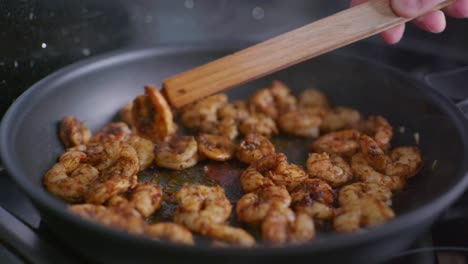 close-up slow motion shot of gently turning prawns in a frying pan with cajun seasoning