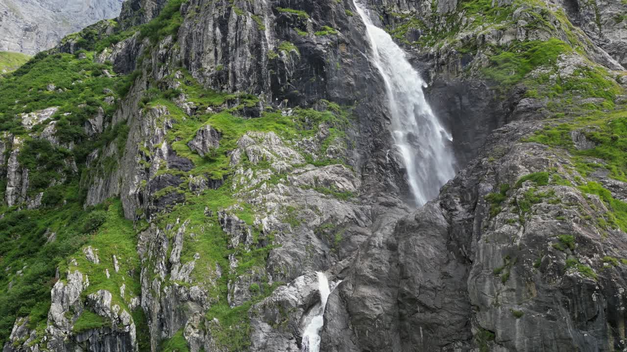 enorme vista aérea de la cascada por drones desde abajo, paso y cara verde de la montaña, alpes, suiza, obwalden