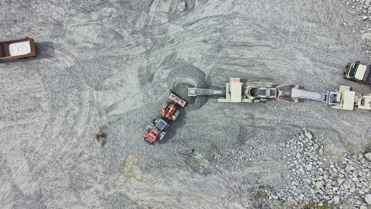 Quarry operations seen from above with machinery working on granite rocks in a stone extraction site