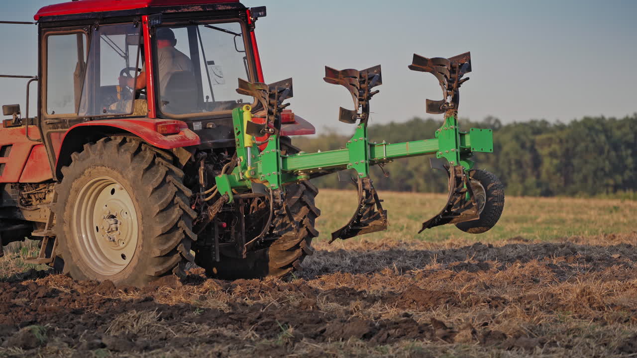 Farmer in tractor customize equipment for cultivating the soil. Close-up view of agricultural tractor in the field at daytime. Seasonal works in rural place.