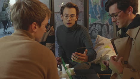 businessmen working together in cafe. coworkers looking at smartphone screen