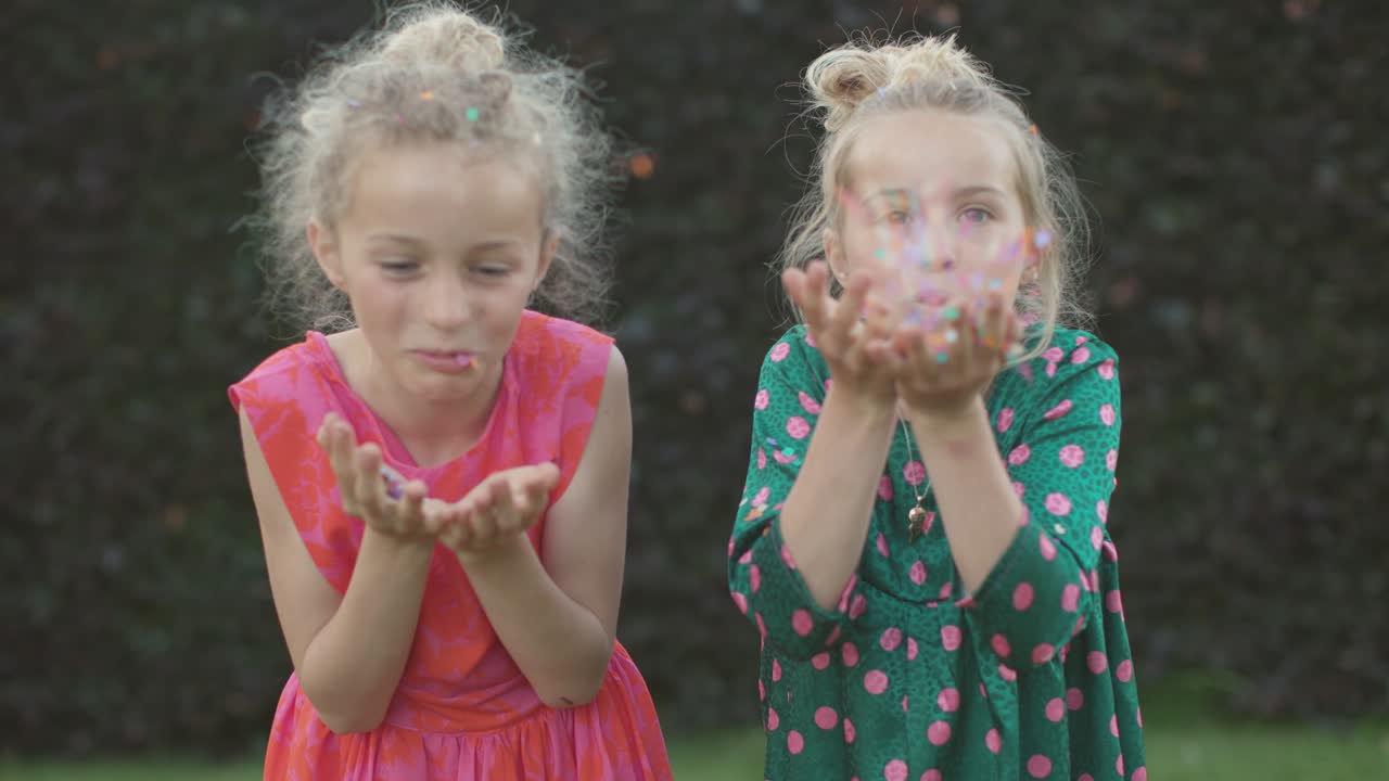 two beautiful little girls playing with confetti in front of the camera - people having fun in slow motion