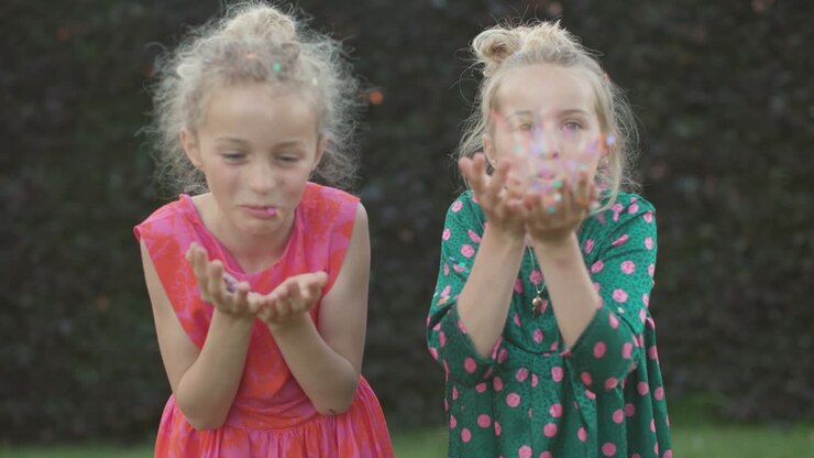 Due bellissime bambine giocano con i coriandoli davanti alla telecamera - persone che si divertono al rallentatore.