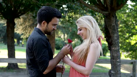 young man makes marriage proposal to blonde woman in the park