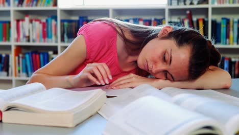 tired schoolgirl sleeping in library while doing homework