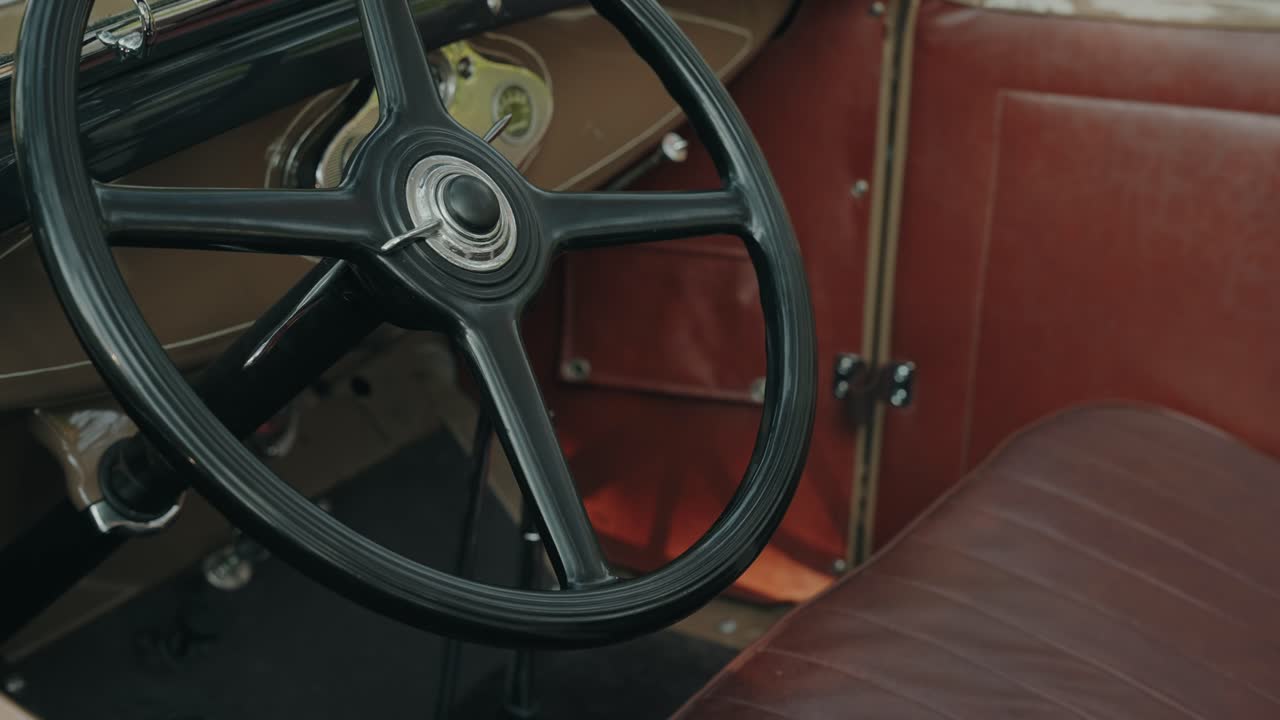 검은색 핸들과 갈색 가죽 실내 장식이 보이는 고급스러운 오래된 자동차 내부의 클로즈업