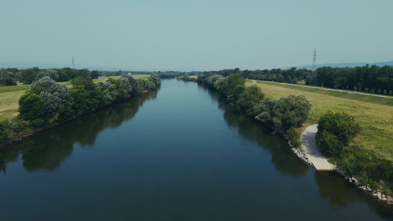 aerial - calm Sava River flows through rural Zagreb outskirts bordered by trees and grasslands