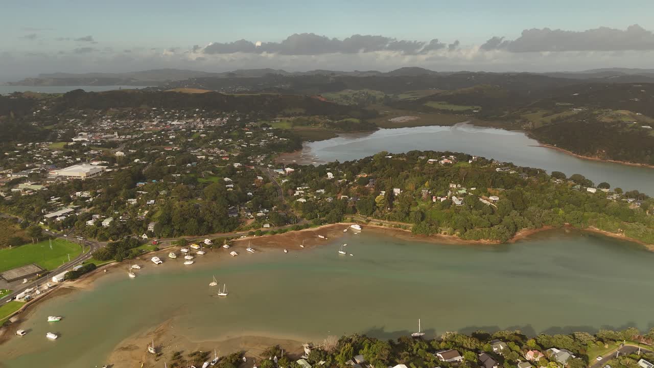 Haiheke island with bay and parking boats and sandy beach. Aerial wide shot. Foggy sunset time. Panorama view. Tropical landscape with city.