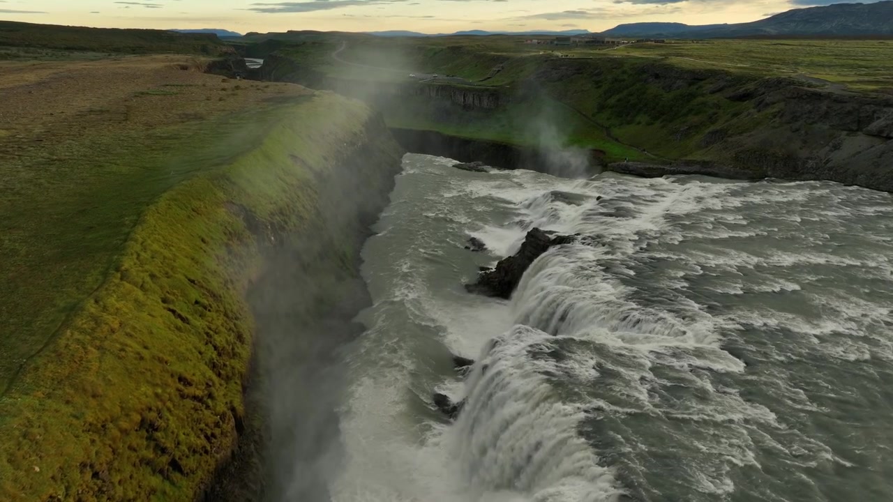 Fantastisk flygvy över Gullfoss vattenfall på Island, som visar kraftfullt forsande vatten, gröna landskap och dramatisk naturskönhet.