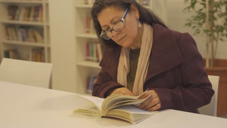 senior argentinian reading literature books at library