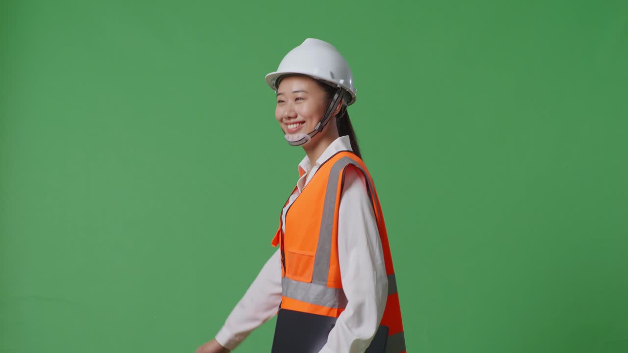 녹색 화면 배경 스튜디오에서 는 동안 태블릿을 들고 있는 안전 헬을 입은 아시아 여성 엔지니어의 측면 시각