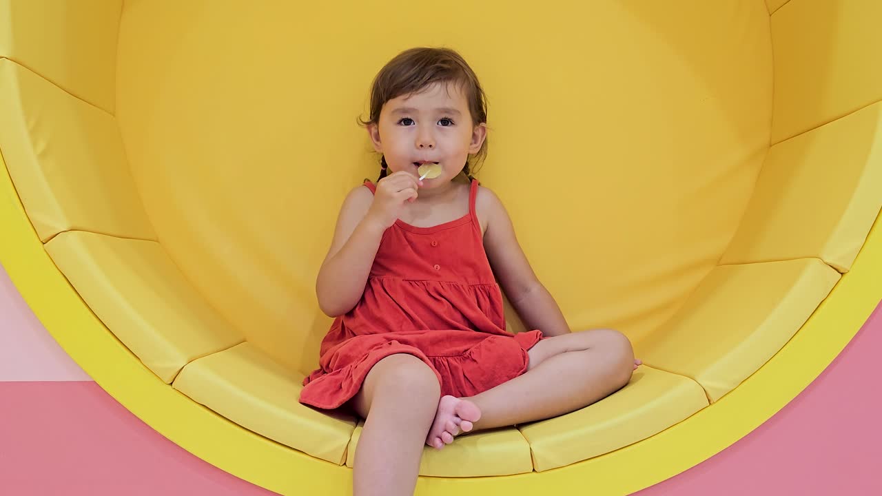 Smiling happy toddler child girl sucking yellow lollipop Premium Stock Video Footage