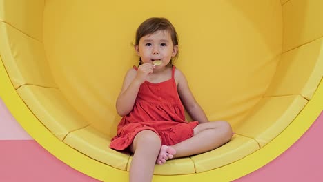 smiling happy toddler child girl sucking yellow lollipop