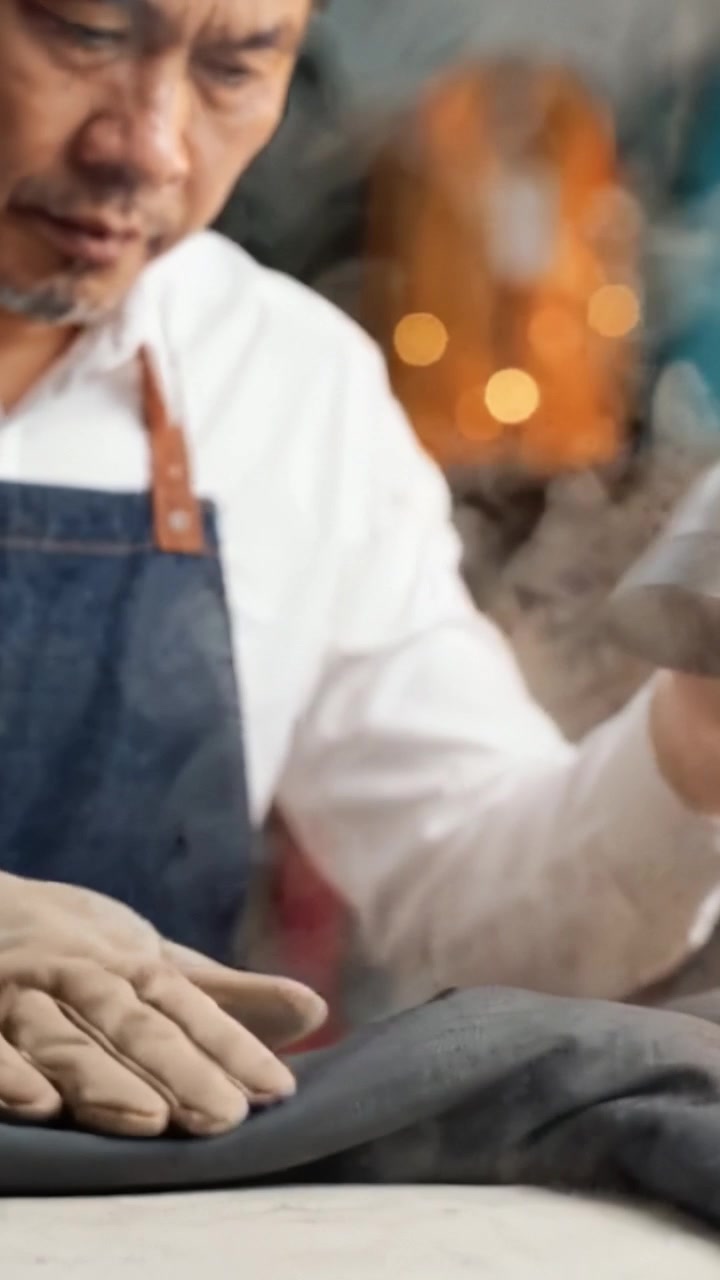 Sarto esperto che stira a vapore con cura pantaloni grigi per eliminare le pieghe e garantire un aspetto impeccabile e professionale in un laboratorio di sartoria.