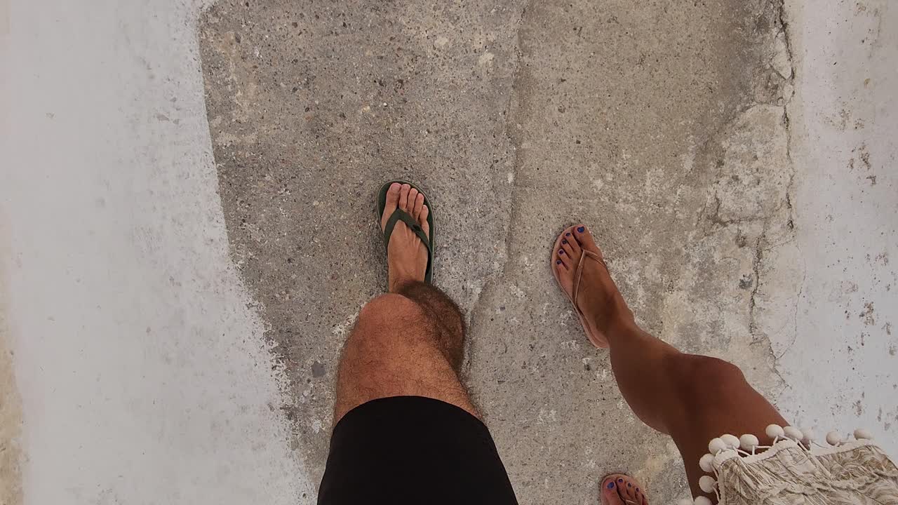 hombre y mujeres paseando con los pies en las vibraciones del verano en una calle griega