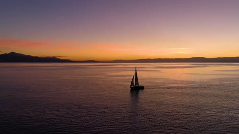 Volando-Bajo-Pasando-Junto-A-Un-Velero-En-El-Lago-Léman-Con-Hermosos-Colores-De-Puesta-De-Sol-Frente-A-Lutry,-Lavaux---Suiza