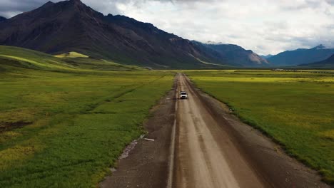 viaje por carretera en una furgoneta a través del valle de portage junto a las montañas de brooks range en el verano de alaska - disparo de seguimiento aéreo con un movimiento hacia atrás