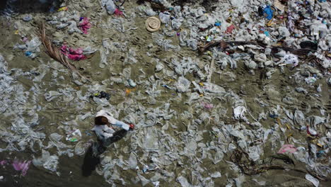 Ocean-pollution,-caucasian-woman-walking-on-sand-beach-covered-with-plastic-waste-rubbish-dump-landfill,-aerial-top-down-climate-change-global-warming-concept