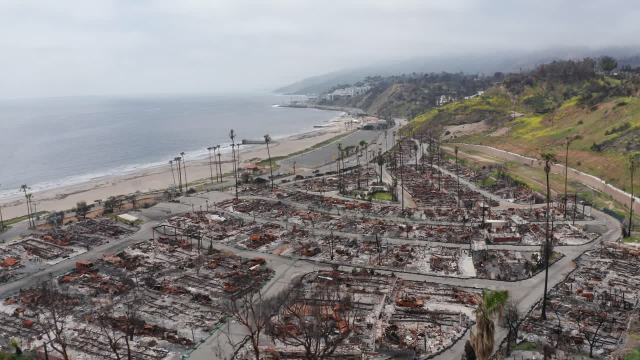 Aerial wide shot flying over a burned residential neighborhood in the aftermath of the Palisades Fire in Los Angeles, California. 4K