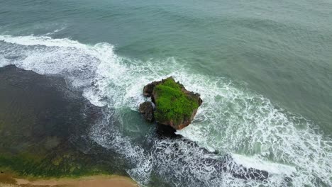 toma aérea de olas rompiendo en la roca de coral cerca de la playa