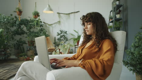 woman using laptop in room with green plants