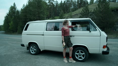 woman standing by van and petting dog