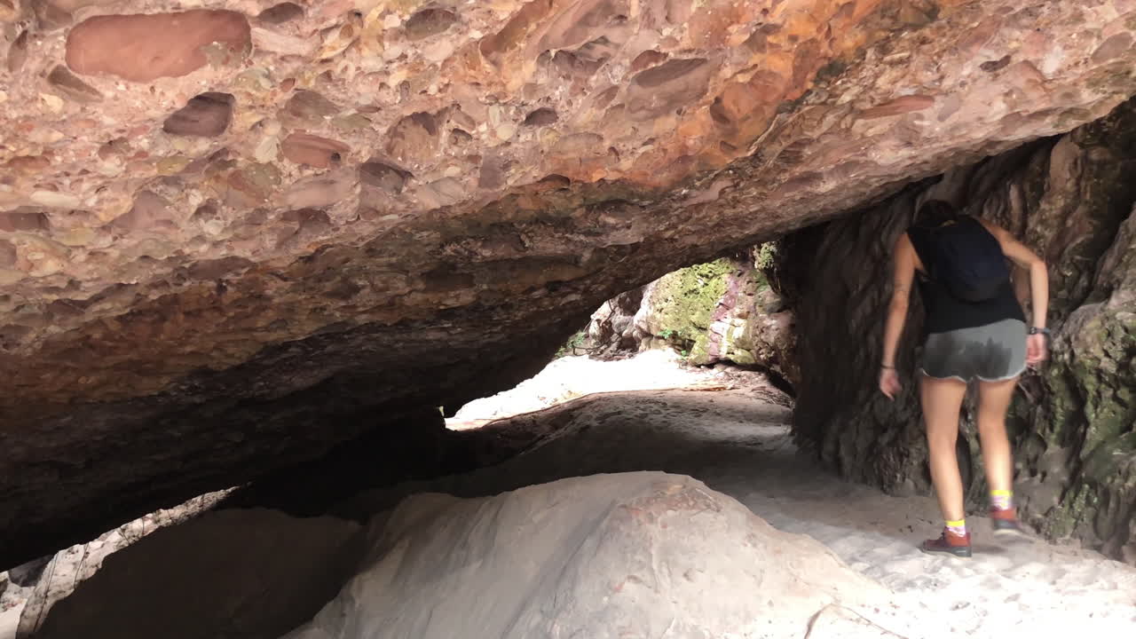 Young woman adventurer walks away in cave exit in Chapada Diamantina Brazil, slowmotion