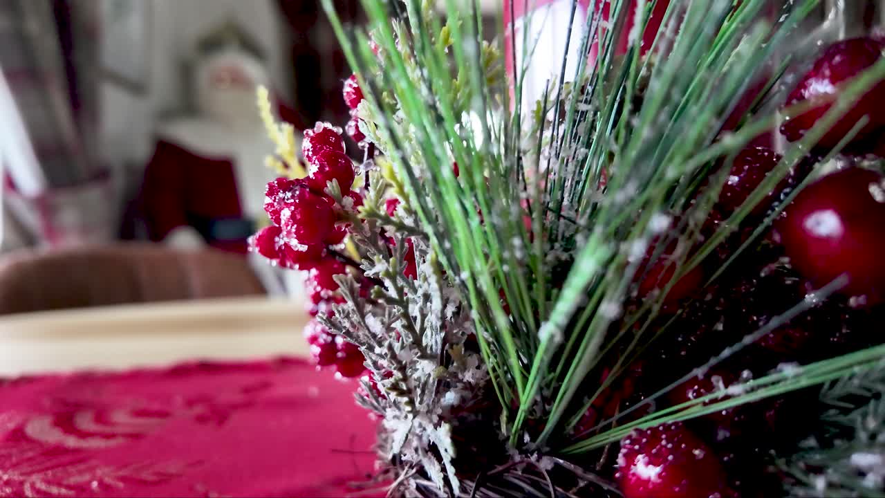 Decorazione natalizia festiva da tavola con bacche rosse e vegetazione e una statuetta di Babbo Natale sullo sfondo