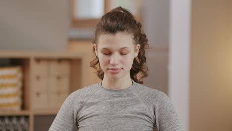 Close-frontal-view-of-young-woman-doing-mindfulness-workout-at-home