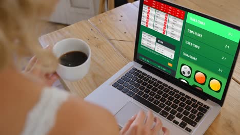 woman watching football score on laptop