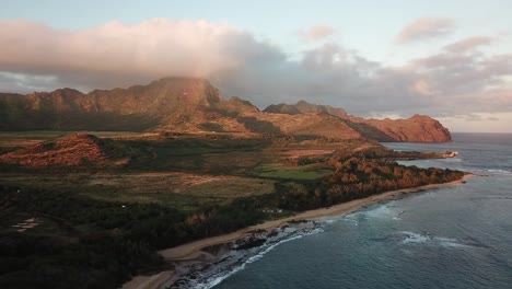 Mountain-with-rainbow-and-ocean-and-beach-at-sunset-in-Kauai,-Hawaii
