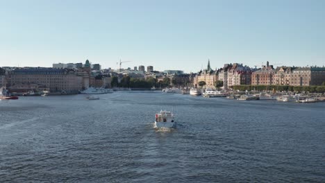 Boat-cruising-in-Ladugårdlandsviken-towards-Nybrokajen-and-Strandvägen-in-Stockholm,-Sweden-during-sunny-evening