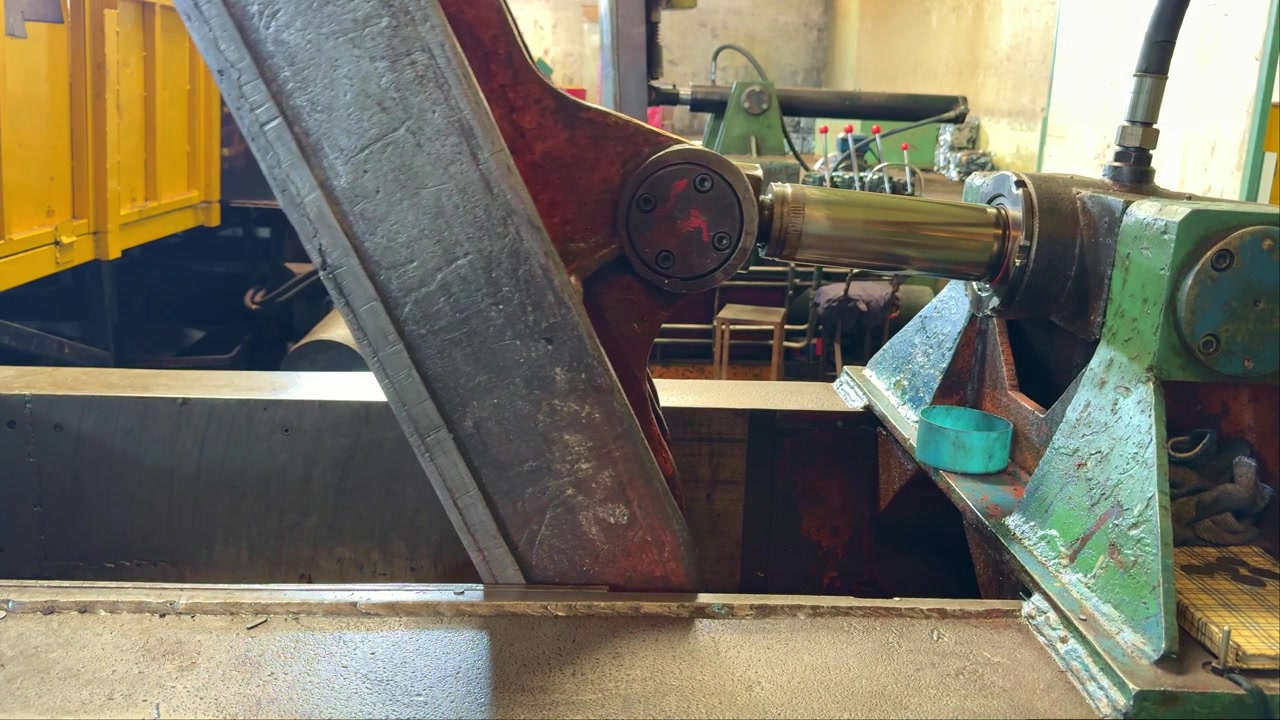 Cilindro hidráulico acionando equipamentos industriais em uma fábrica. O movimento detalhado da maquinaria destaca a automação, a engenharia de precisão e os processos de produção de alta capacidade.