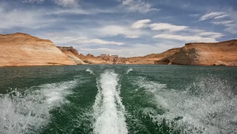 wake of a jet ski boat riding through red canyons of lake powell in utah