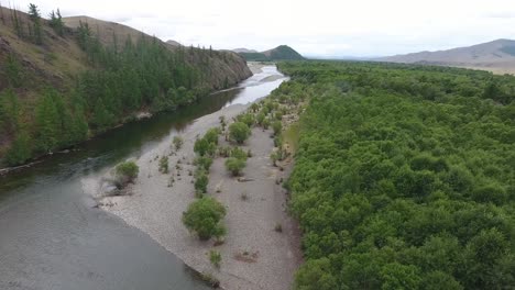 aerial drone shot following a river in mongolia . cloudy day