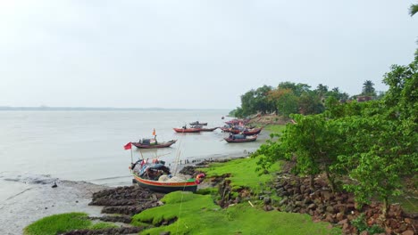 fishing boats moored along a green riverbank under an overcast sky