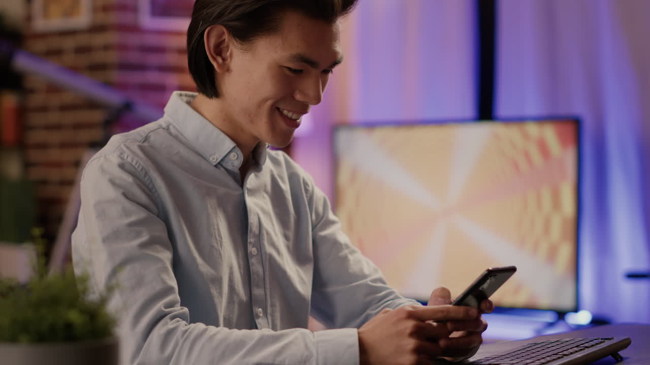 Man using smartphone at desk with computer