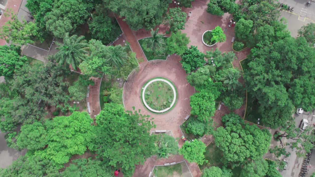 Aerial zenithal shot with spiral zoom out of a circular park in Yopal, Colombia, surrounded by trees and pathways