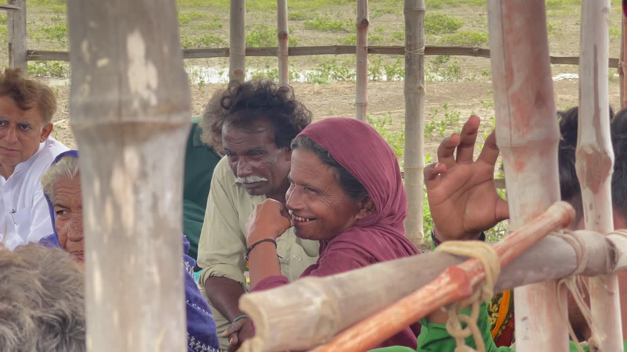 Group of people gathered under a bamboo shelter in Keti Bandar, Sindh, rural atmosphere. Pakistan