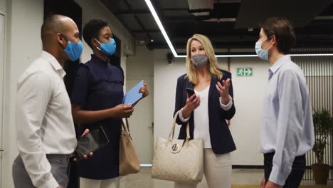 Diverse business people wearing face masks talking in office