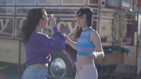Two Women Dancing in Front of a Vintage Bus