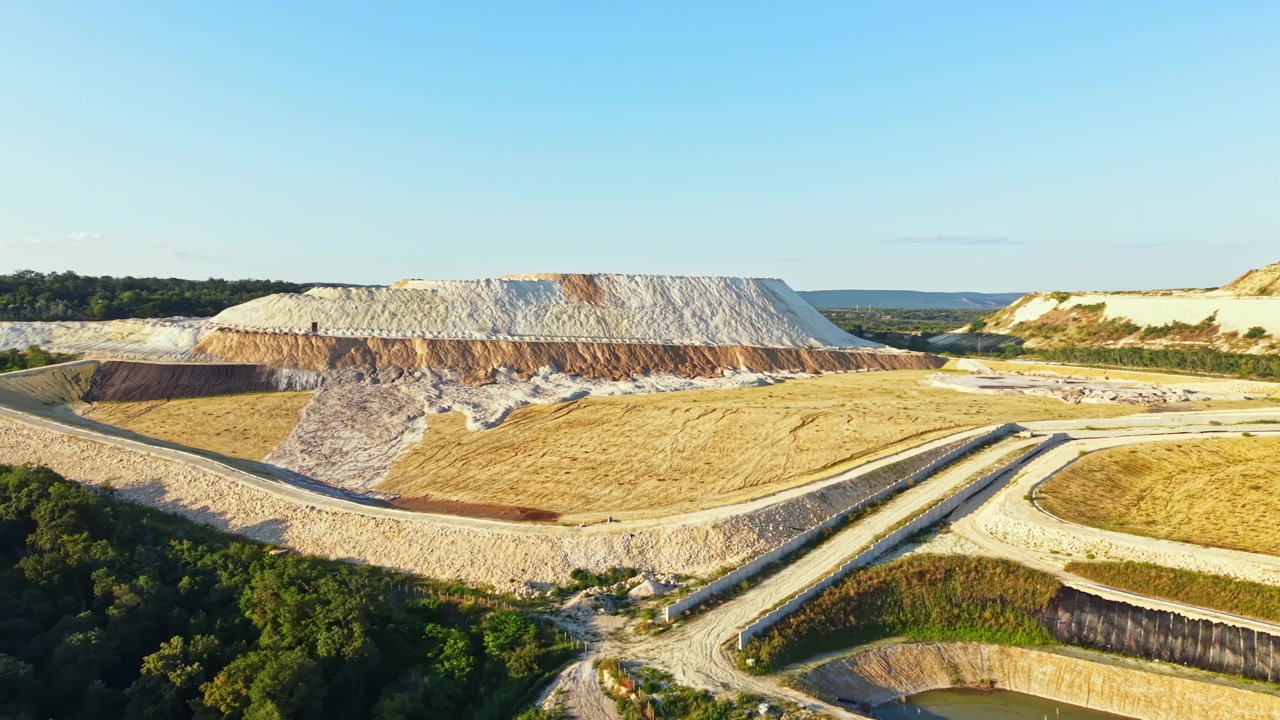 Vasta area di terreno che mostra una cava con pendii e colline sotto un cielo sereno di giorno